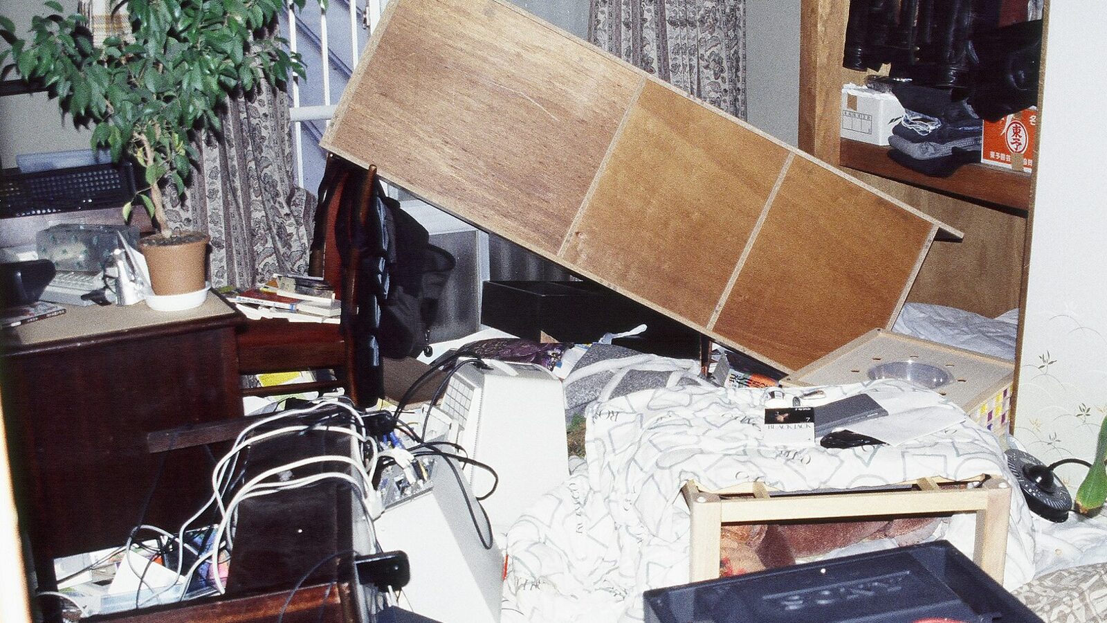 阪神・淡路大震災で倒れた棚がベッドの上に覆いかぶさった部屋。